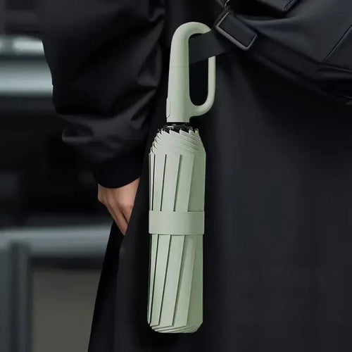 Folded compact umbrella with large hook handle attached to black bag, modern minimalist design